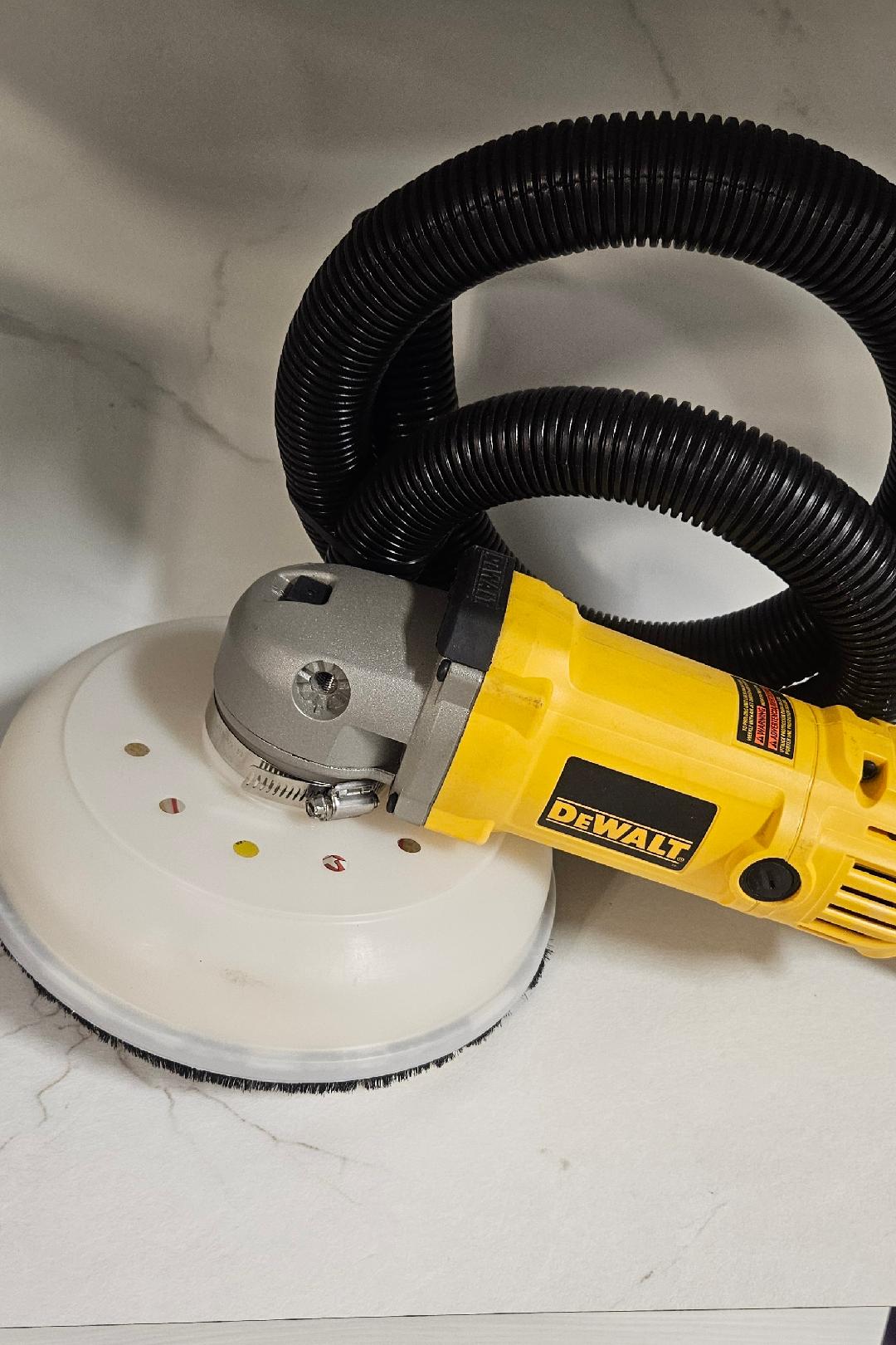 KS100 patented dust collector hood mounted on a DeWalt 7-inch grinder with corrugated vacuum hose, photographed against a clean studio backdrop
